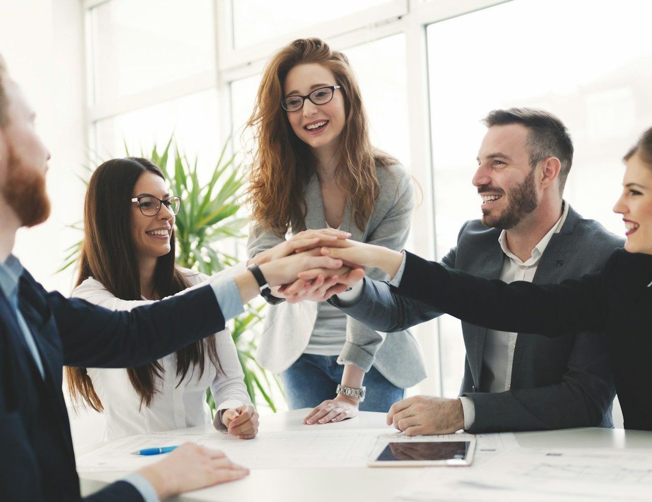 A group of business people are putting their hands together in an office.