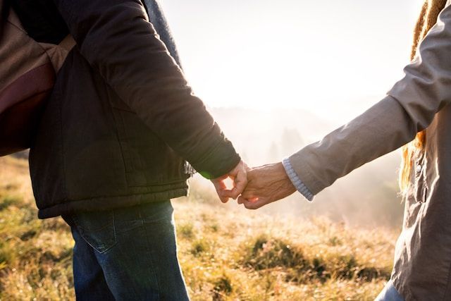 A man and a woman are holding hands in a field.