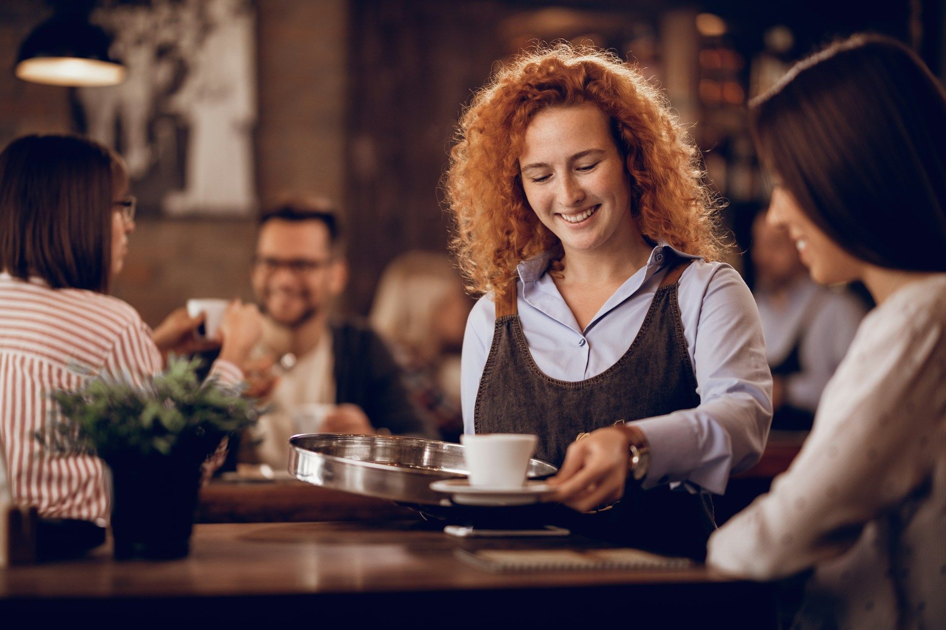 A waitress is serving a cup of coffee to a group of people in a restaurant.