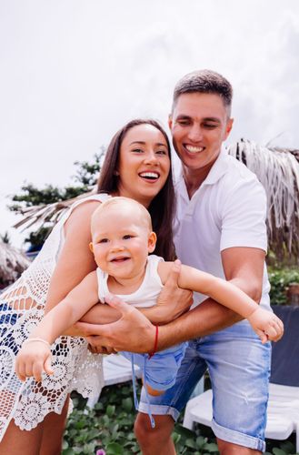 A man and a woman are holding a baby in their arms.