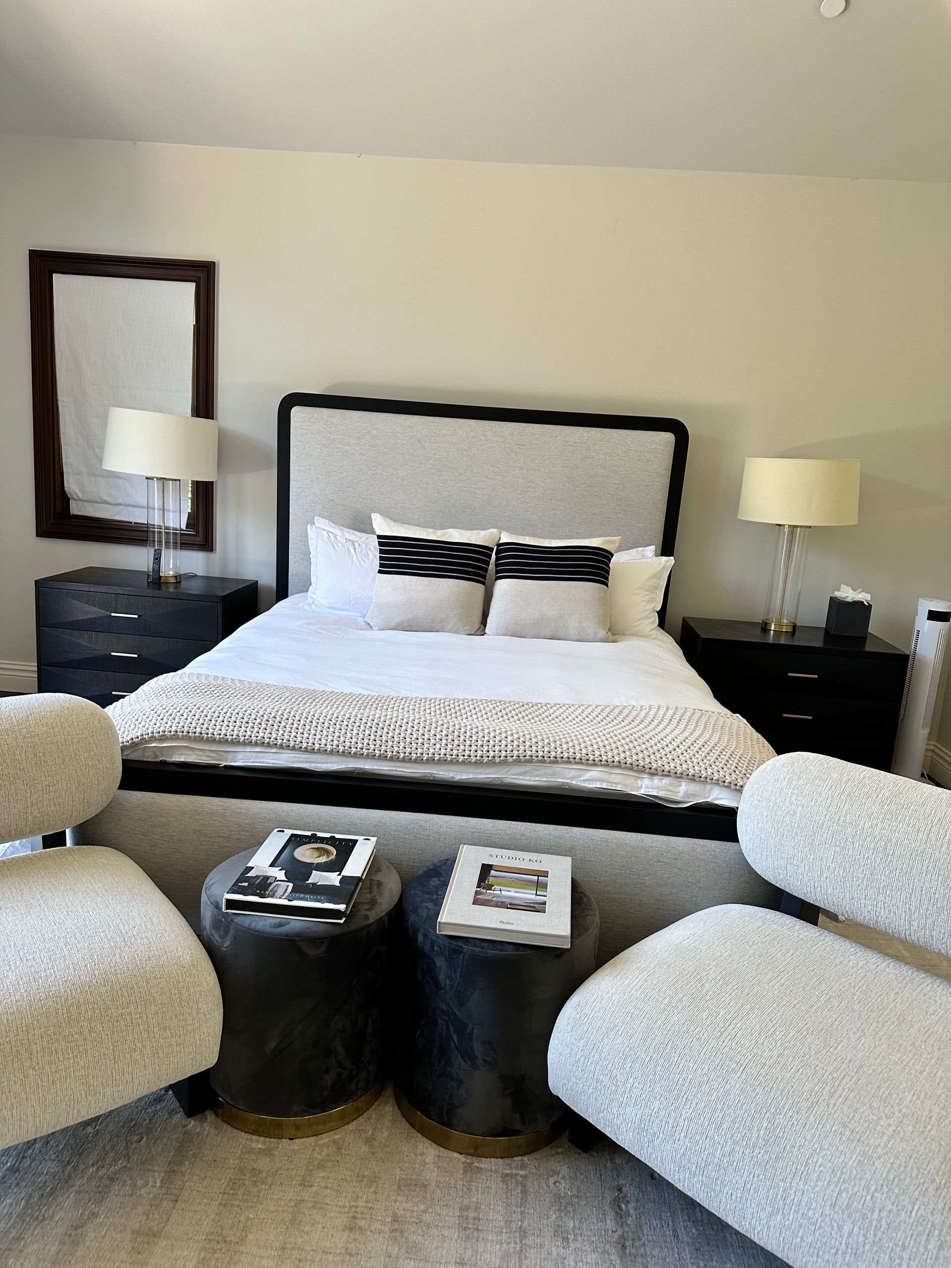 A bedroom with a bed , chairs , lamps and a mirror.