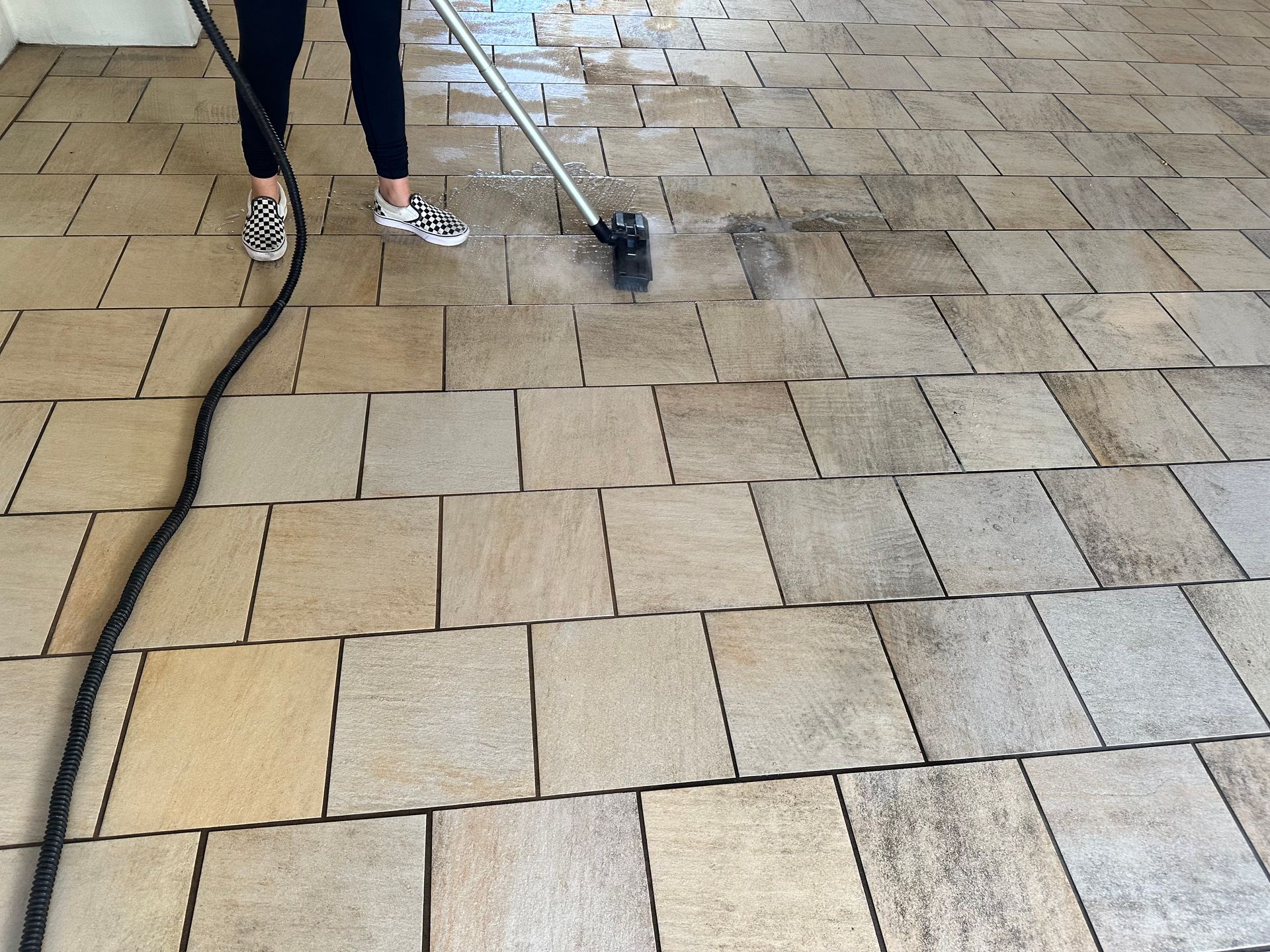 A person is cleaning a tiled floor with a mop