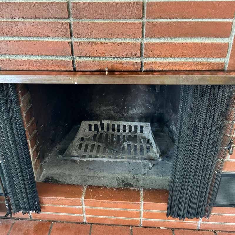 A brick fireplace with a metal grate on top of it.