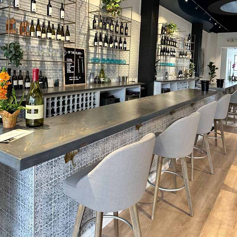 A bottle of wine is sitting on a counter in a restaurant.