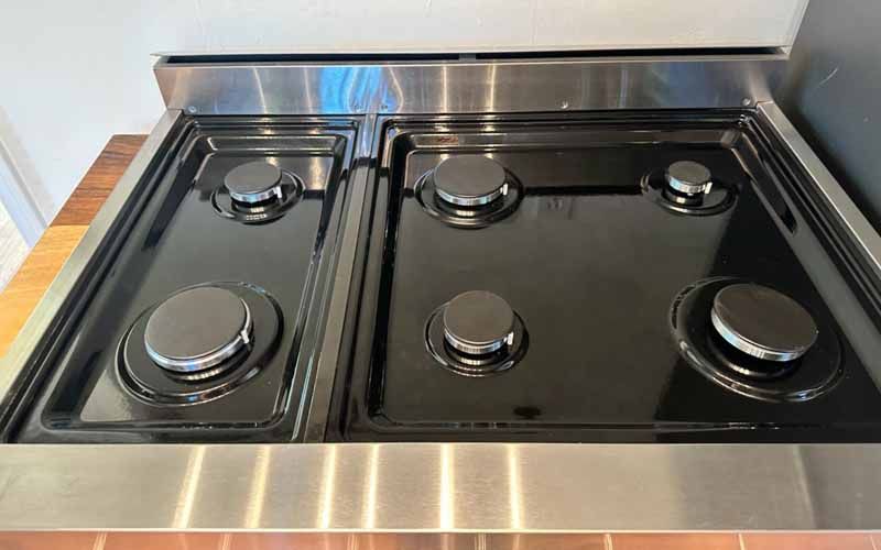 A black gas stove with four burners and a stainless steel frame.