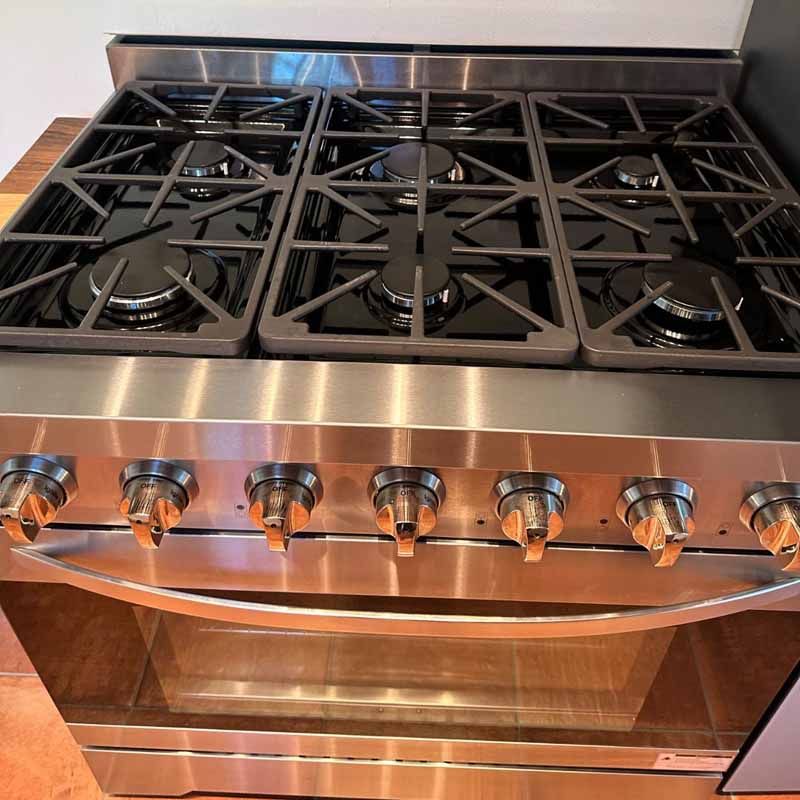 A stainless steel stove with four burners and a glass door