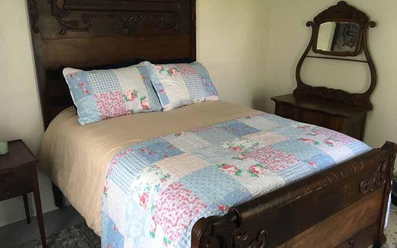 A bedroom with a bed , nightstand , mirror and dresser.