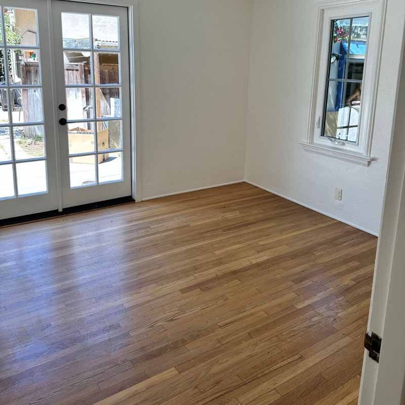 An empty room with hardwood floors and french doors.