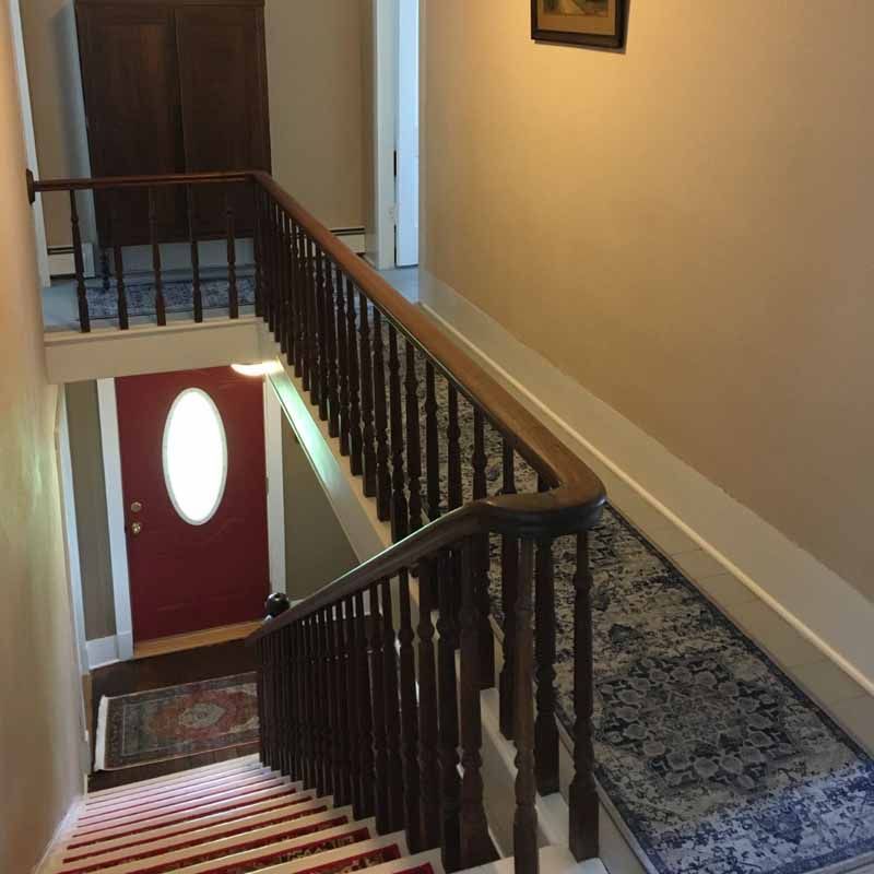 A staircase with a wooden railing and a red door