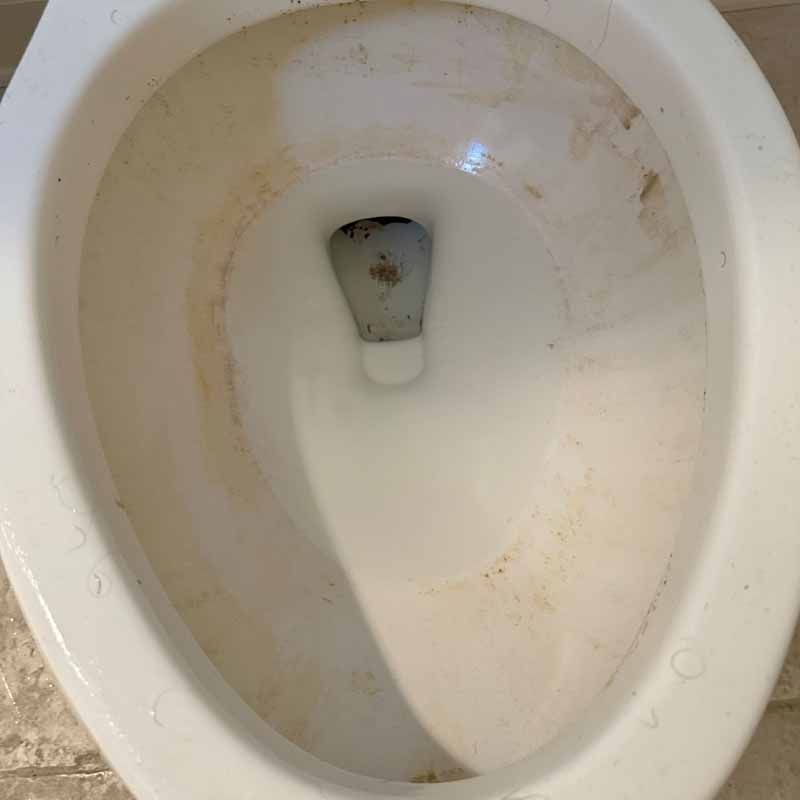 A close up of a dirty toilet bowl in a bathroom.