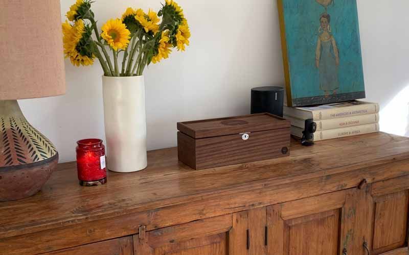 A wooden dresser with a vase of sunflowers and a candle on it.