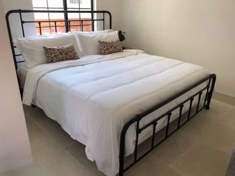 A bed with white sheets and pillows in a bedroom.