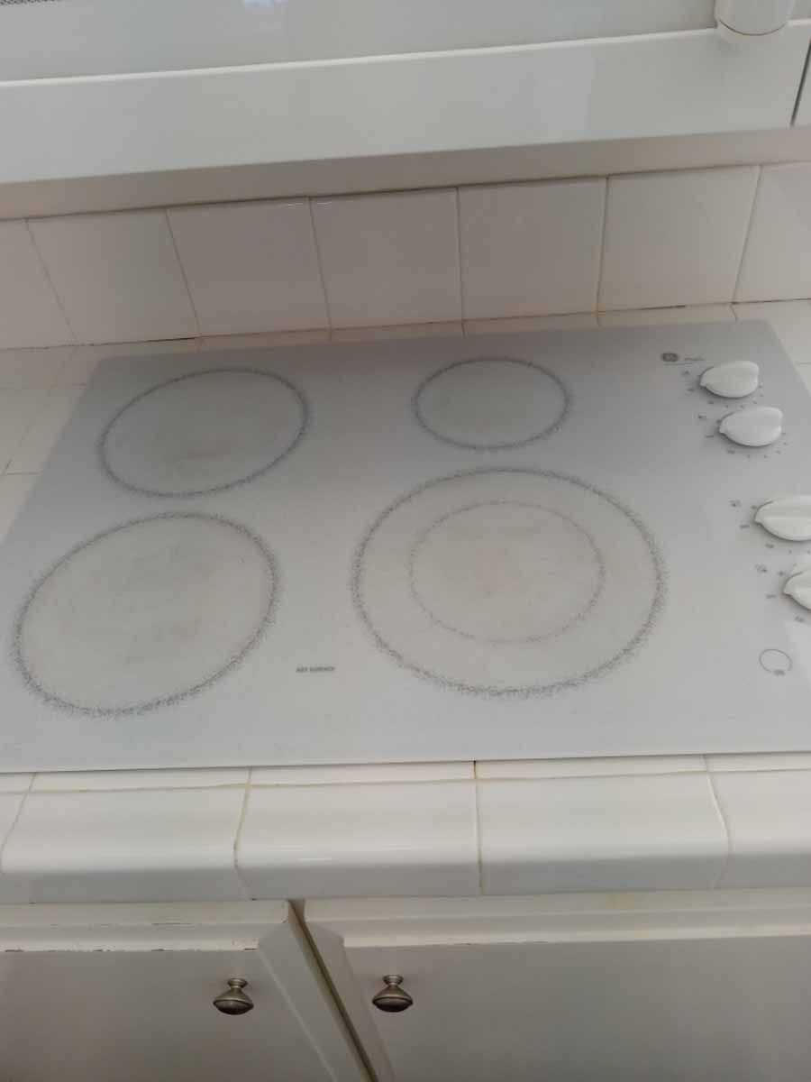 A white stove top with four burners on it