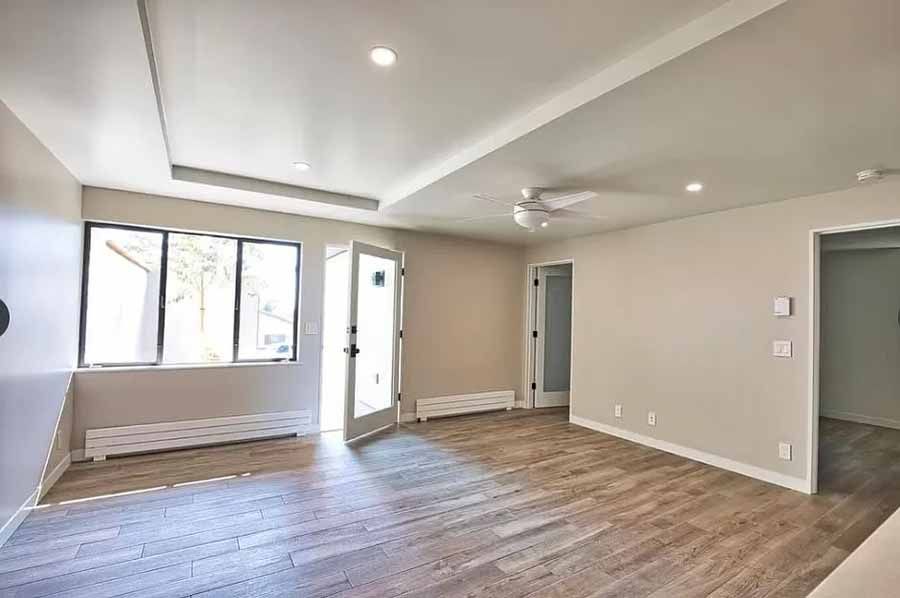 An empty living room with hardwood floors and a ceiling fan.