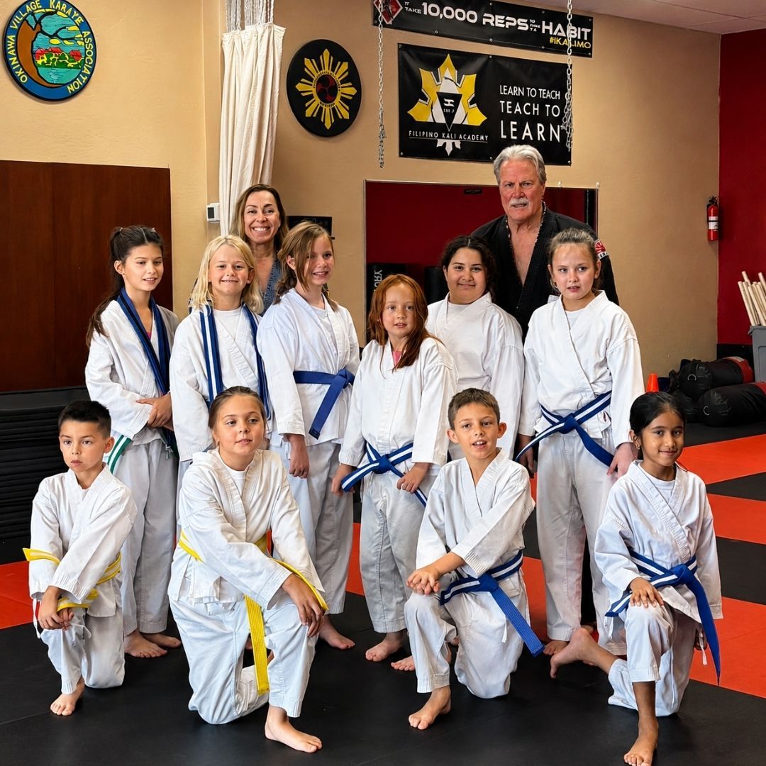 Two boys on a mat practicing Jiu-Jitsu. One boy is on top, giving a thumbs-up.