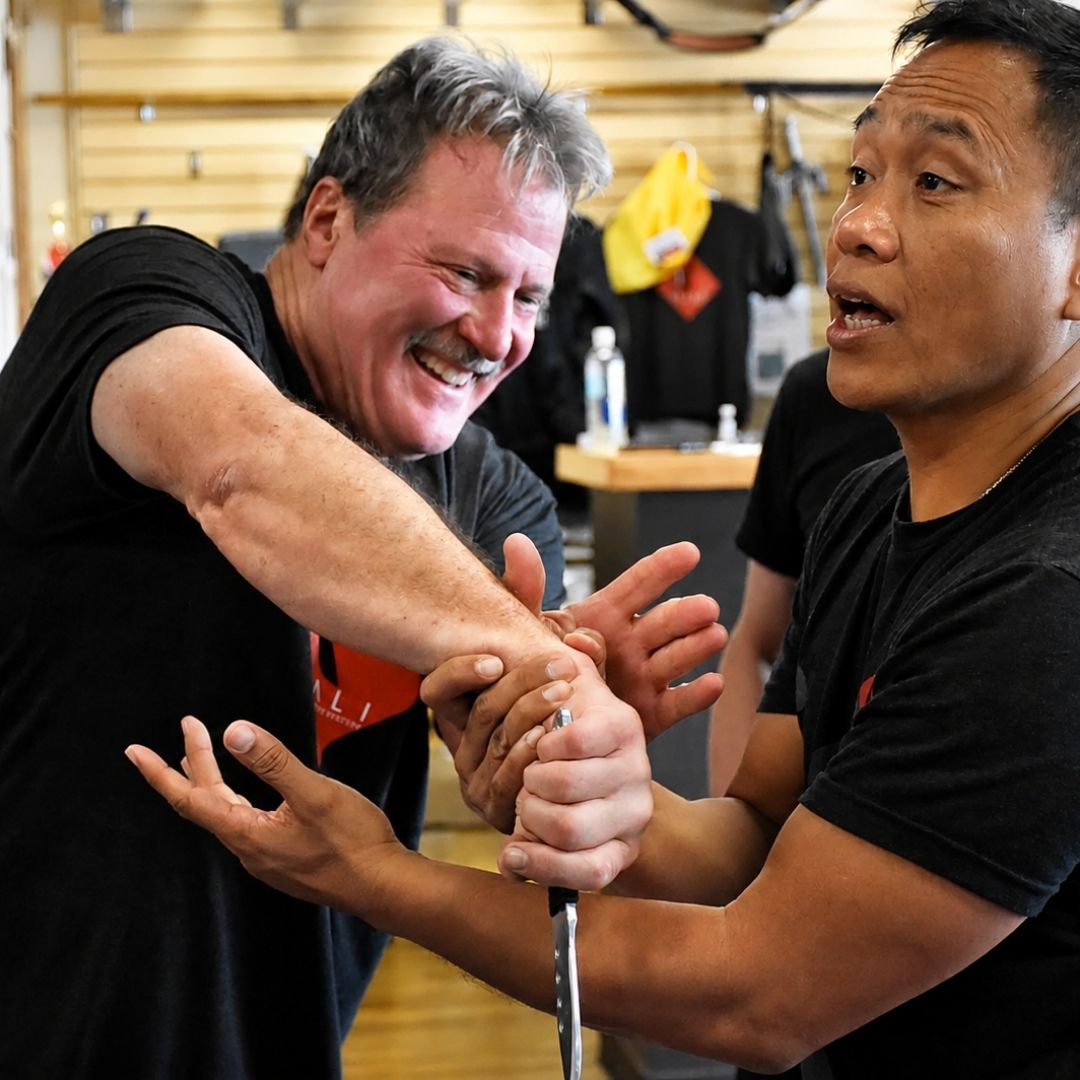 Two people practicing Brazilian Jiu-Jitsu on a mat; one in a black gi, one in a white gi, grappling.