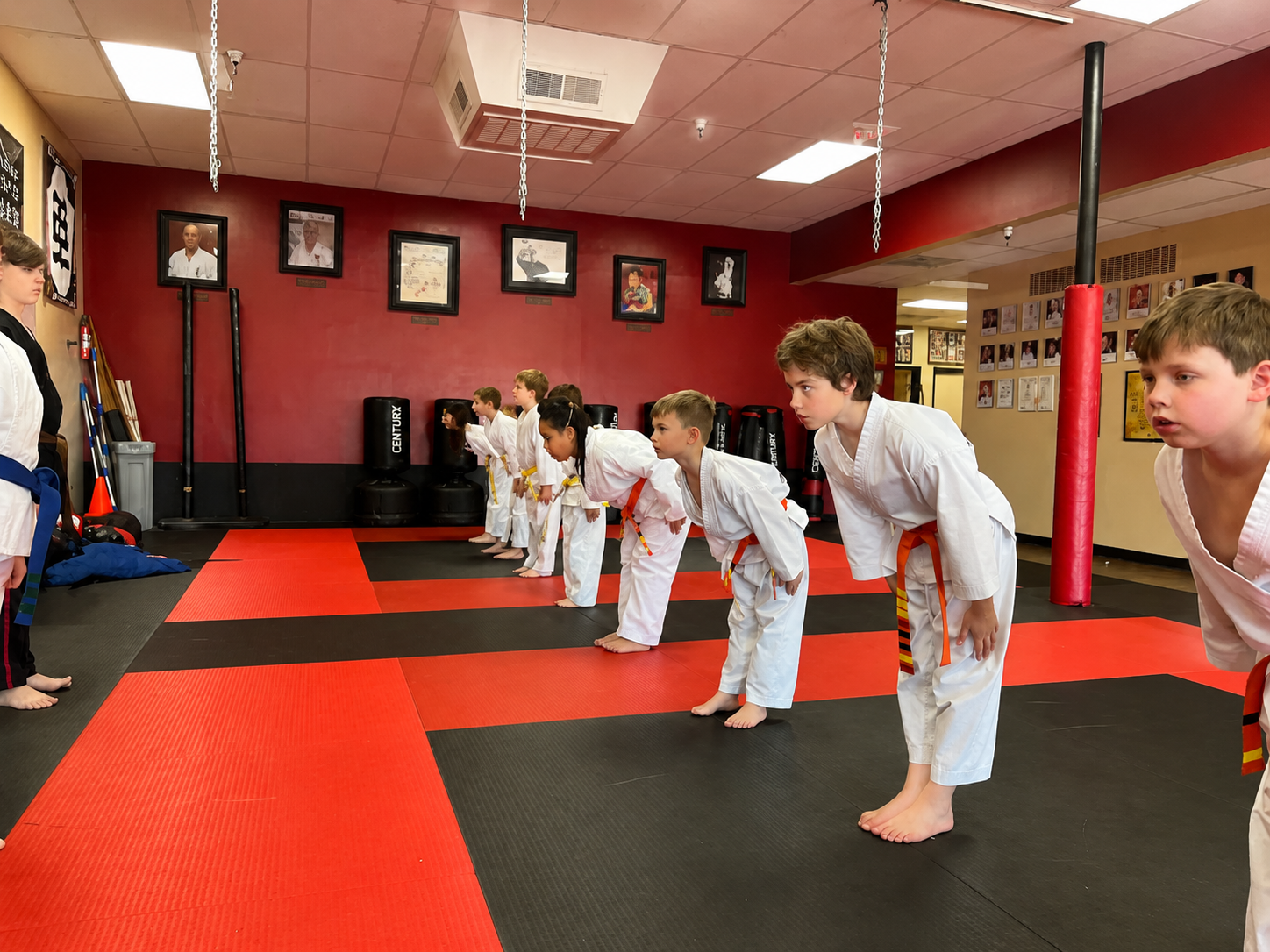 Two people practicing Brazilian Jiu-Jitsu on a mat; one in a black gi, one in a white gi, grappling.