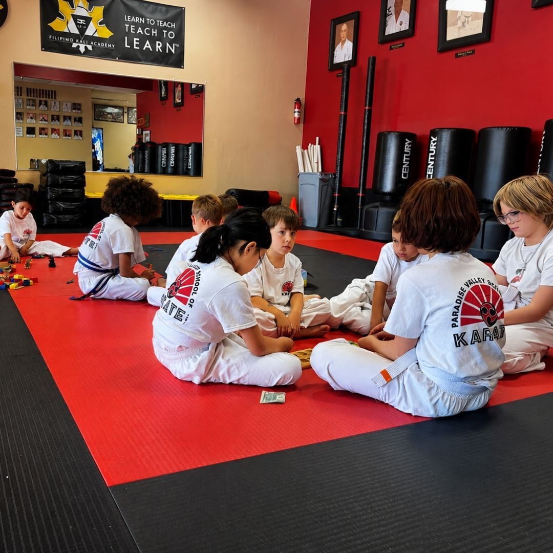 Two boys on a mat practicing Jiu-Jitsu. One boy is on top, giving a thumbs-up.