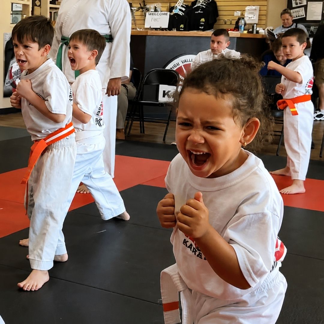 Two people grappling on a mat, one in a black gi, the other in a rash guard, legs entangled.