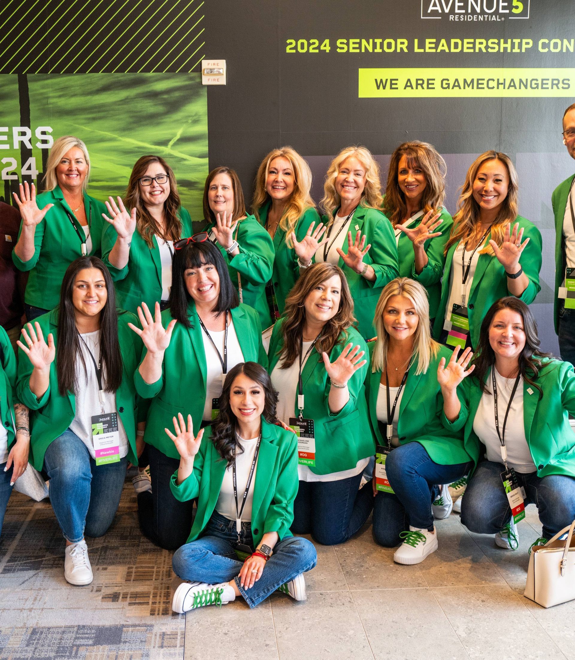 A group of women in green jackets are posing for a picture.