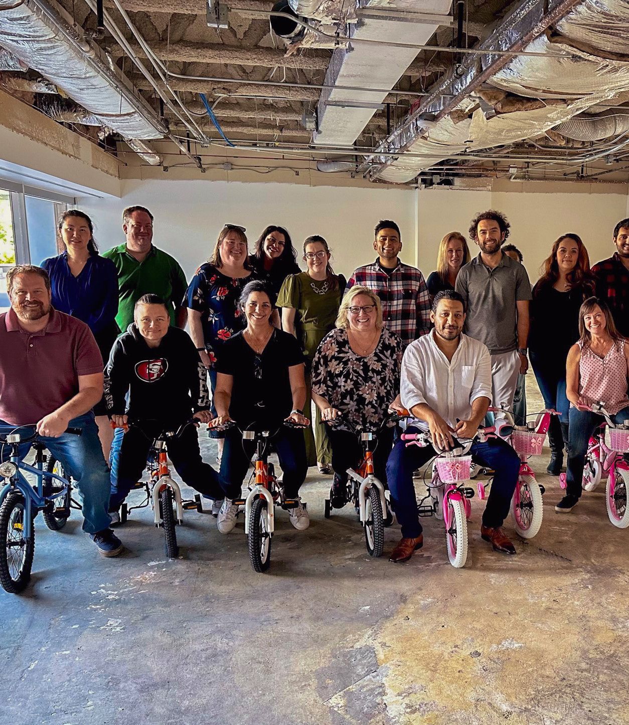 A group of people are posing for a picture with bicycles.