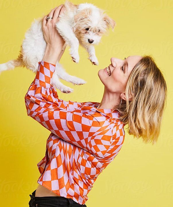 A woman is holding a small dog in her arms.