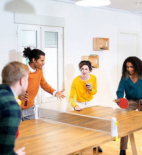 A group of people are playing ping pong at a table.