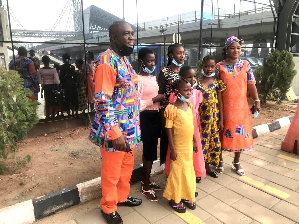 A group of people standing next to each other on a sidewalk.