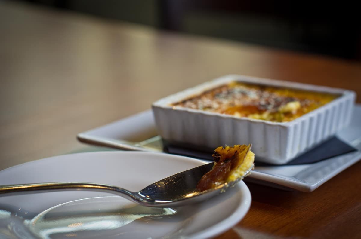 A spoon is sitting on a plate next to a bowl of food.