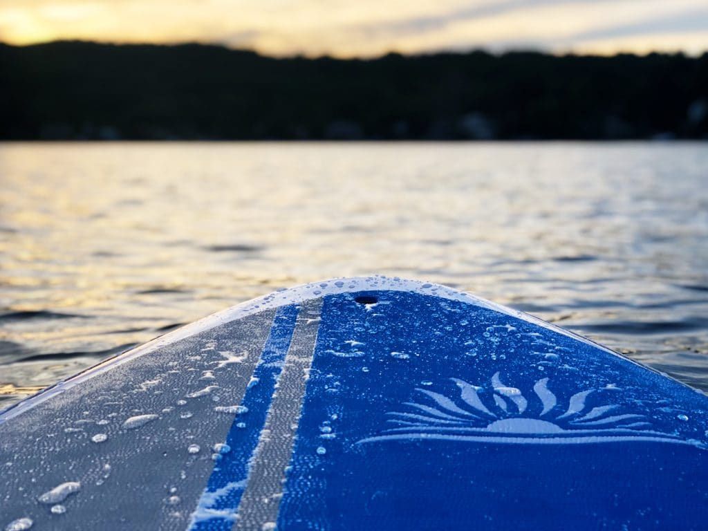 A blue paddle board is floating on top of a body of water.