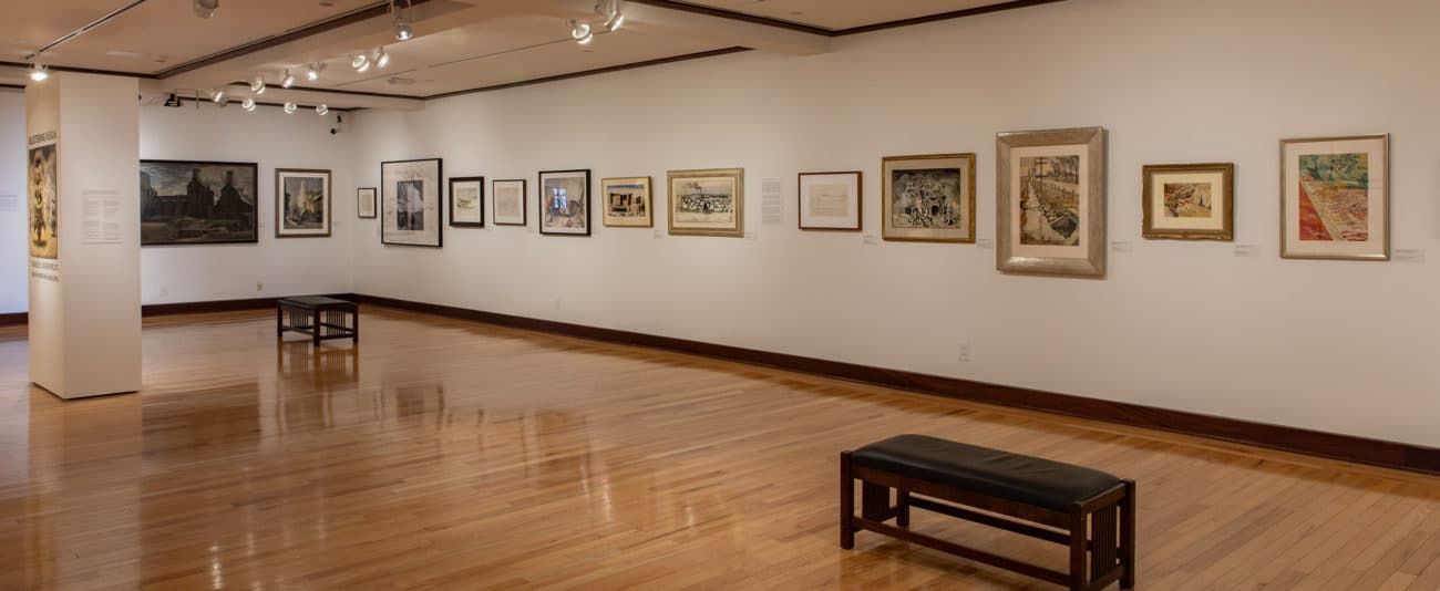 A large empty room with a bench and paintings on the wall.