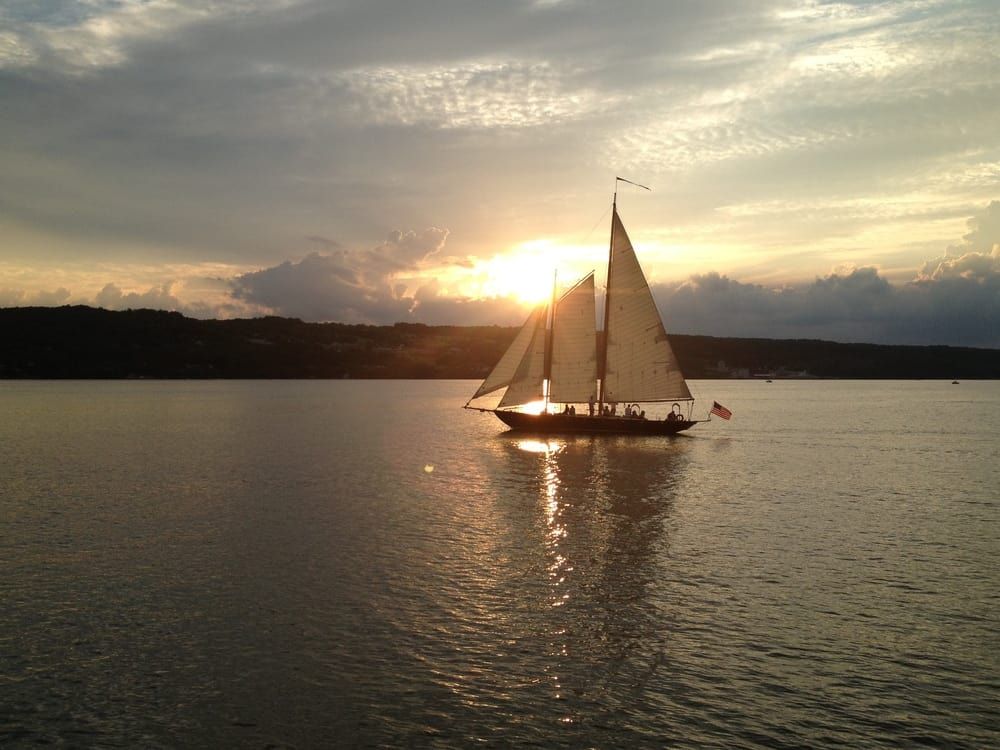 A sailboat is floating on the water at sunset