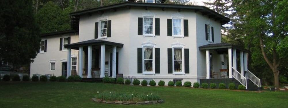 A large white house with black shutters and a porch