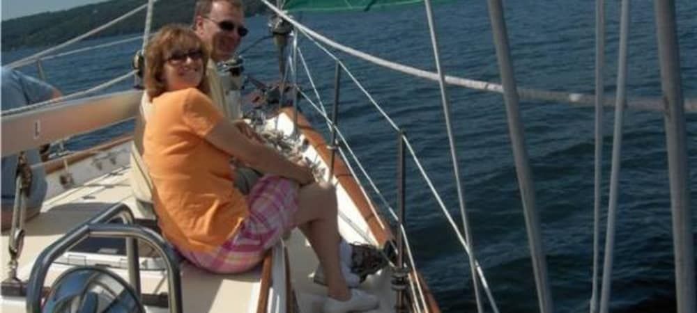 A man and a woman are sitting on a sailboat in the ocean.