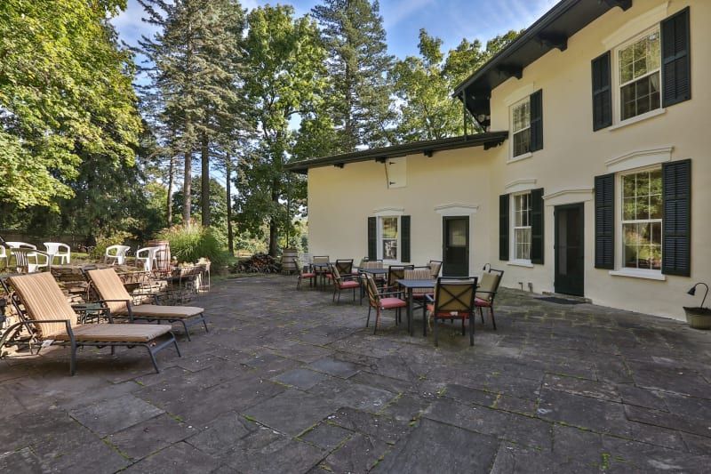 A large white house with a patio with tables and chairs