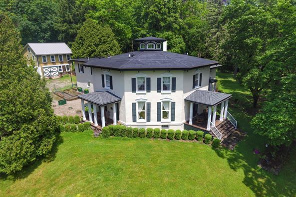 An aerial view of a large white house surrounded by trees.