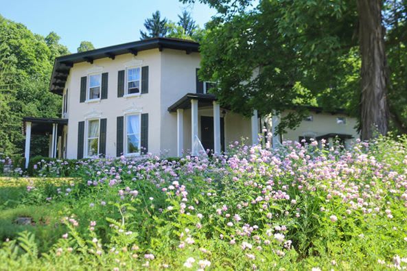 A white house is surrounded by flowers and trees.