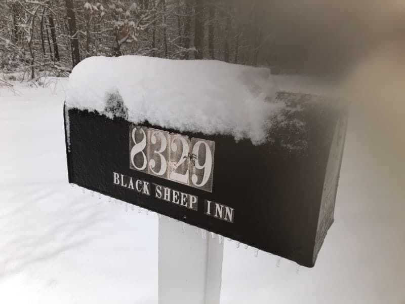 The black sheep inn mailbox is covered in snow