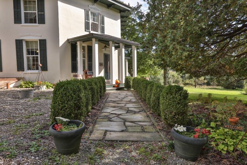 A stone walkway leading to a large white house