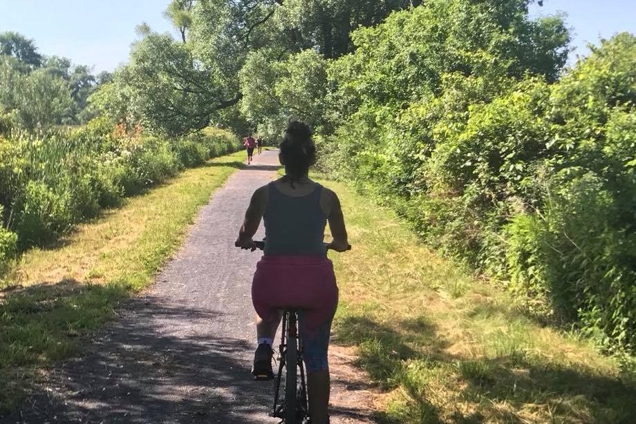 A woman is riding a bike down a path in the woods.