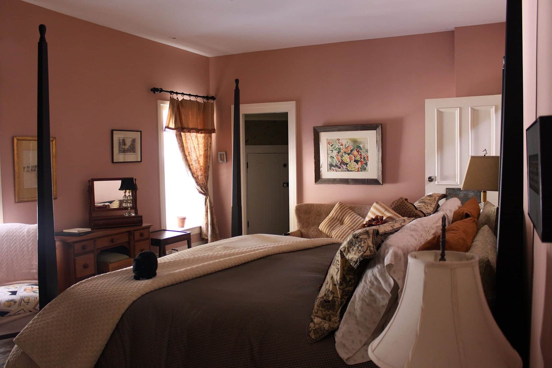 A bedroom with pink walls and a four poster bed