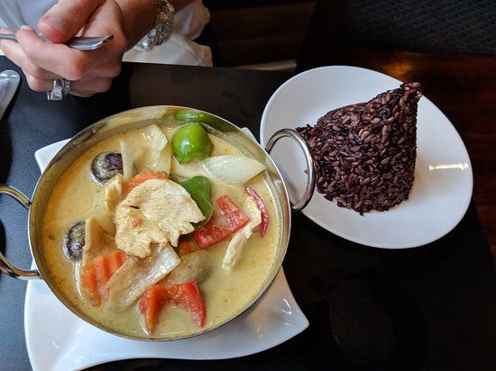 A bowl of soup next to a plate of rice on a table.