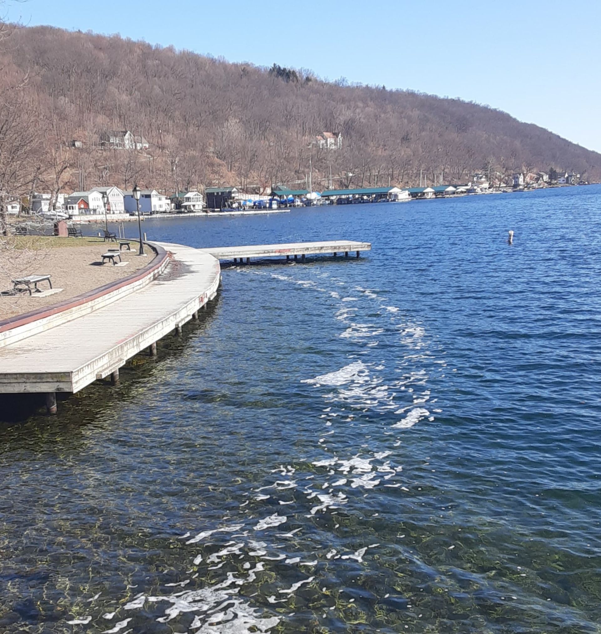 A large body of water with a dock in the foreground and a mountain in the background.