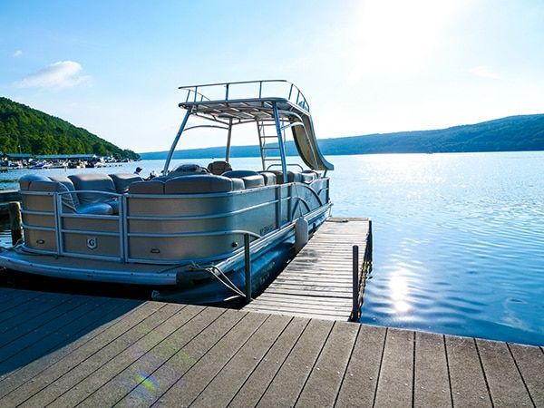 A pontoon boat is docked at a dock on a lake.