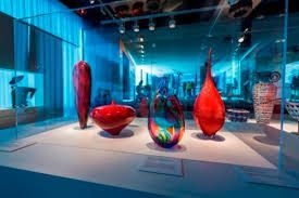 A group of colorful glass vases are on display in a museum.