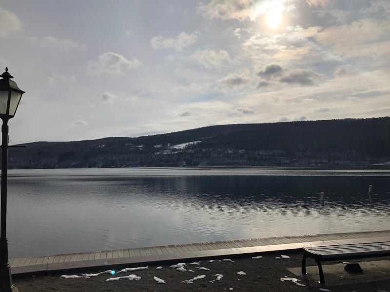 A lake with mountains in the background and a lamp post in the foreground