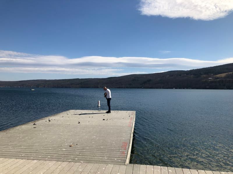 A man is standing on a dock overlooking a lake.