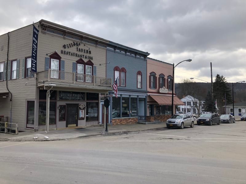 A row of buildings on a city street with cars parked in front of them.