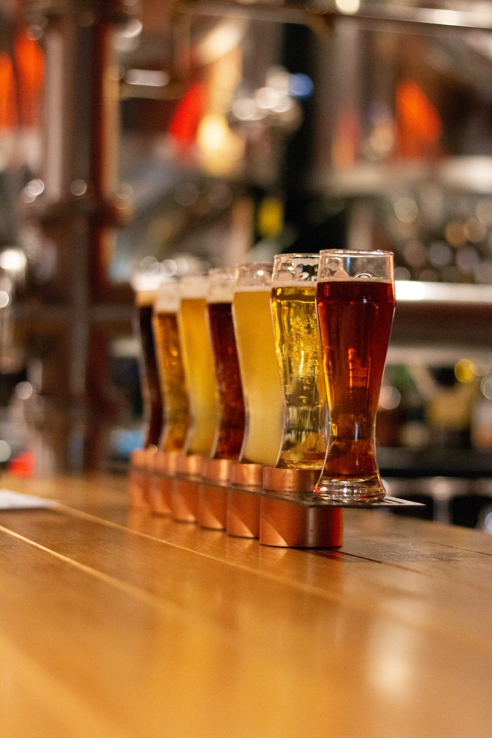 A row of beer glasses sitting on top of a wooden table.