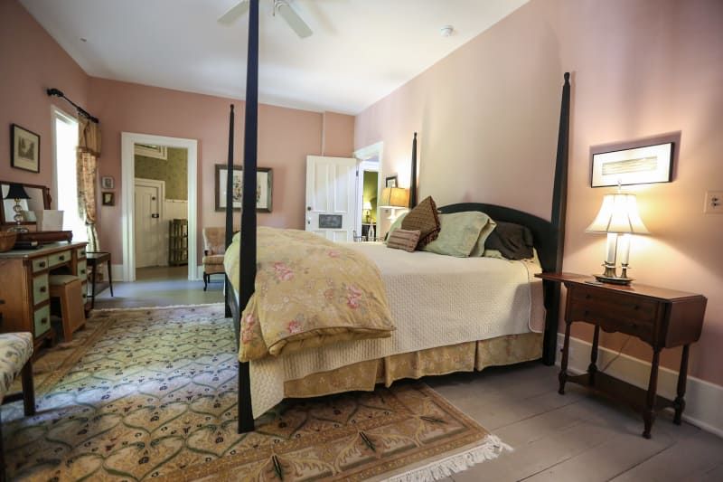 A bedroom with pink walls and a four poster bed